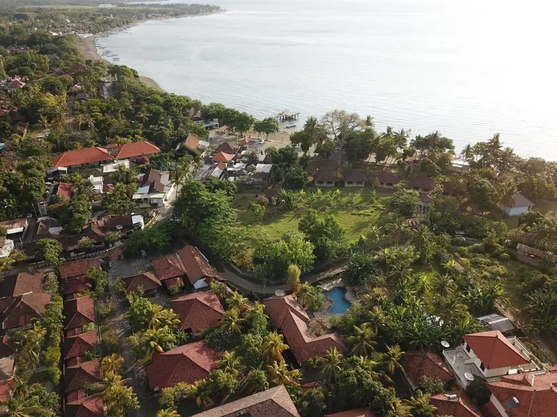 Vue aérienne d'un complexe hôtelier tropical avec des bâtiments aux toits rouges et une végétation luxuriante.