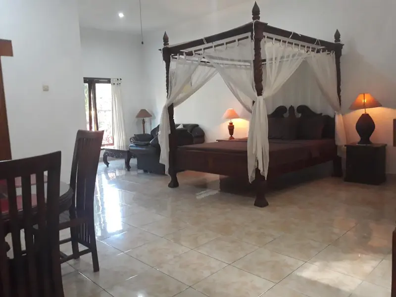 Une chambre spacieuse avec un lit à baldaquin en bois sombre et des meubles en bois.