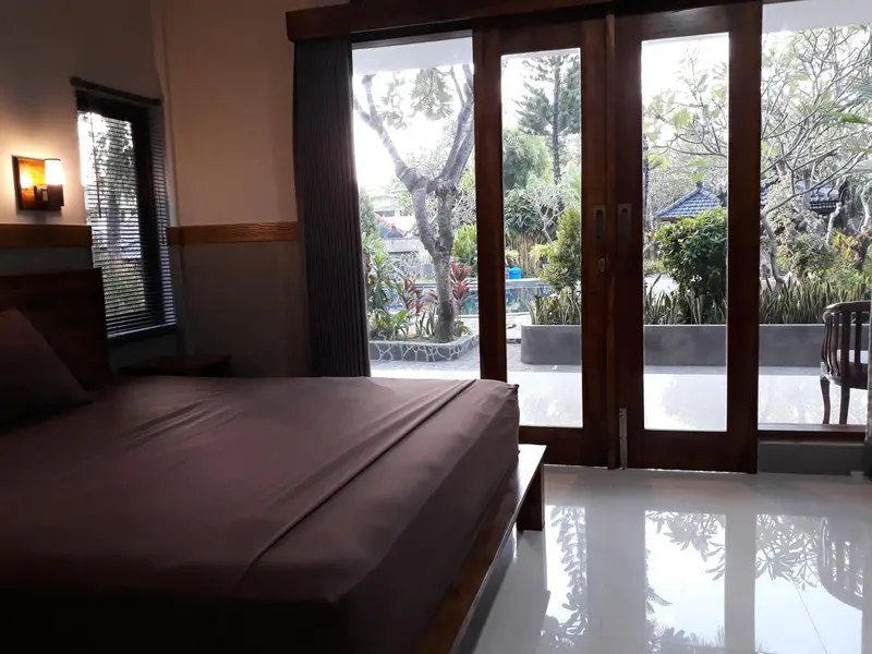 Une chambre lumineuse s'ouvre sur une terrasse verdoyante.