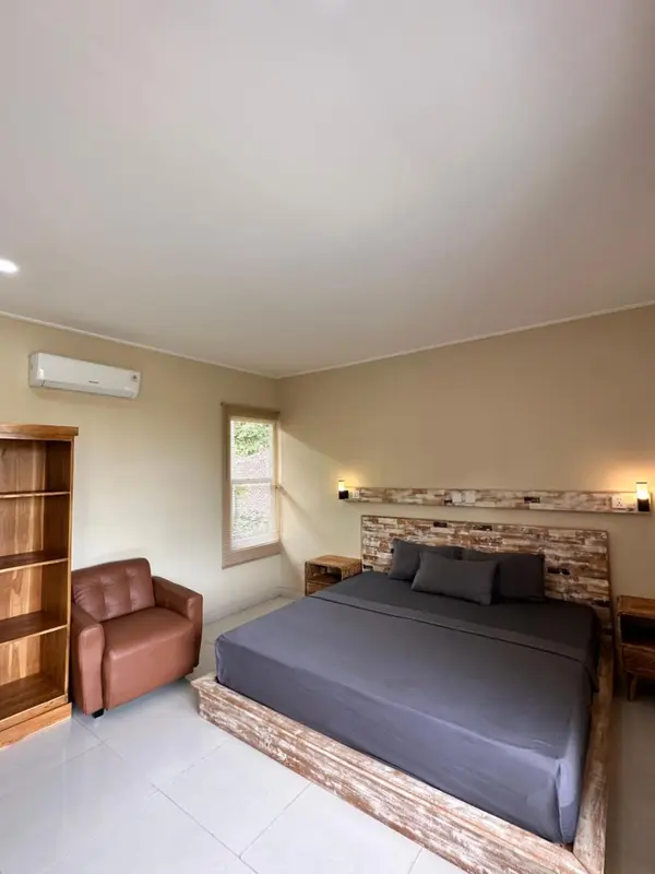 Une chambre lumineuse avec un grand lit et un fauteuil.
