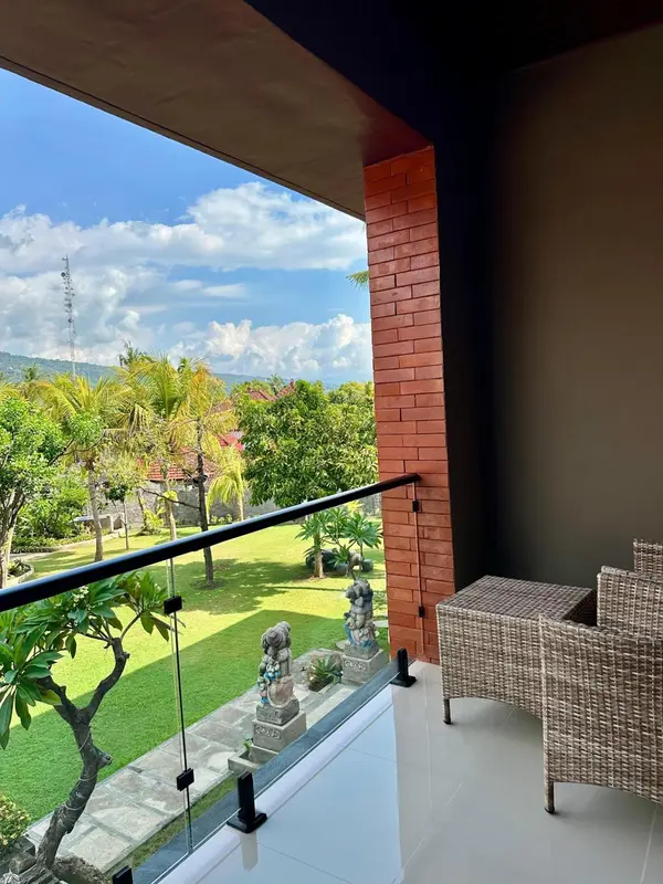 Terrasse avec mobilier d'extérieur donnant sur un jardin verdoyant et une vue lointaine.