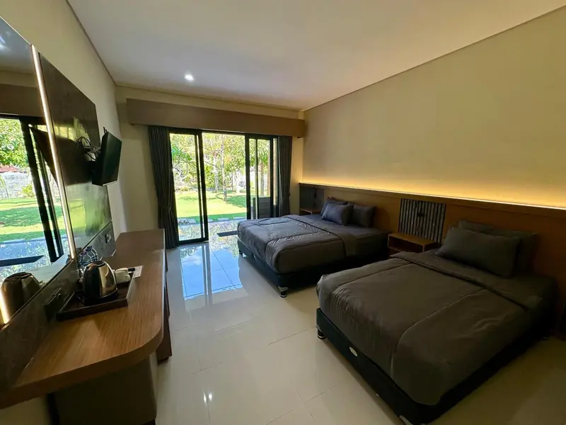 Une chambre lumineuse avec deux lits et une vue sur la végétation.