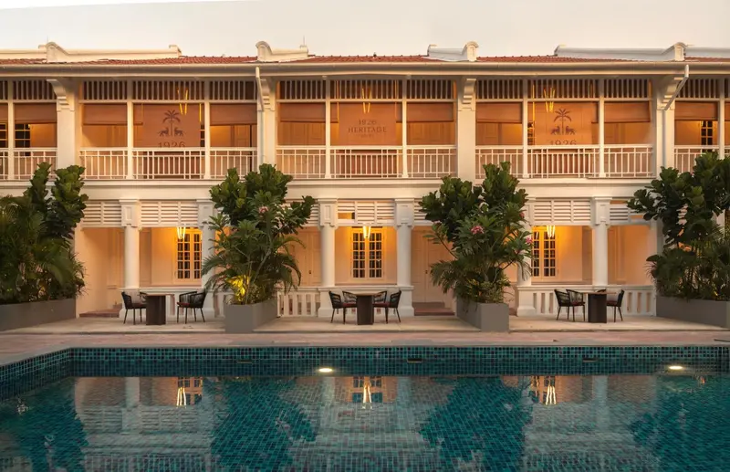 Façade d'un bâtiment colonial avec une piscine au premier plan.