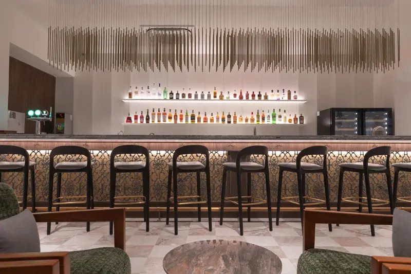 Un long comptoir de bar avec des tabourets est éclairé par des suspensions décoratives.