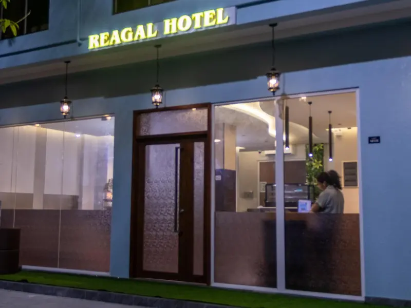 Façade d'un hôtel avec une entrée lumineuse et un comptoir d'accueil.