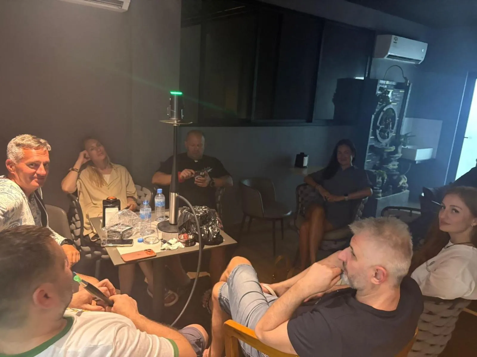 Des personnes sont assises autour d'une table dans une pièce sombre.