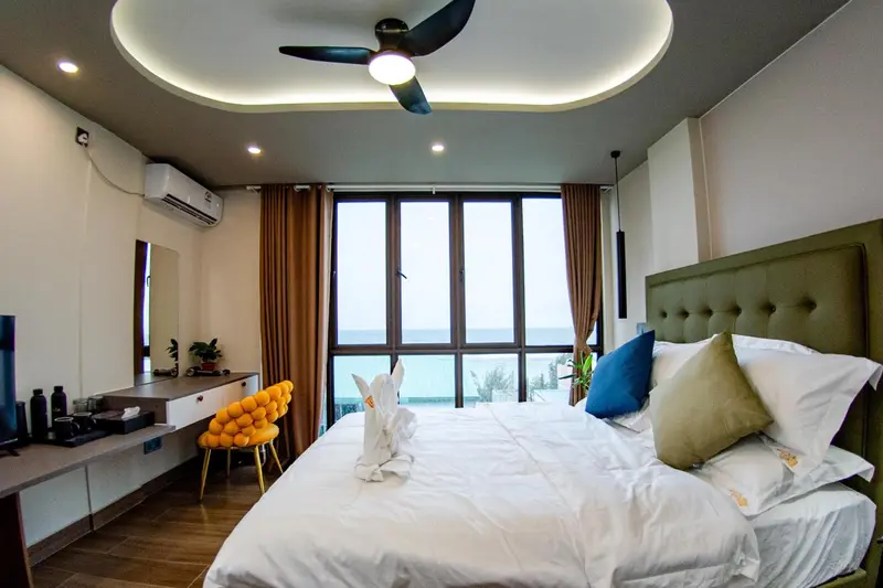 Chambre lumineuse avec un grand lit et vue sur la mer.