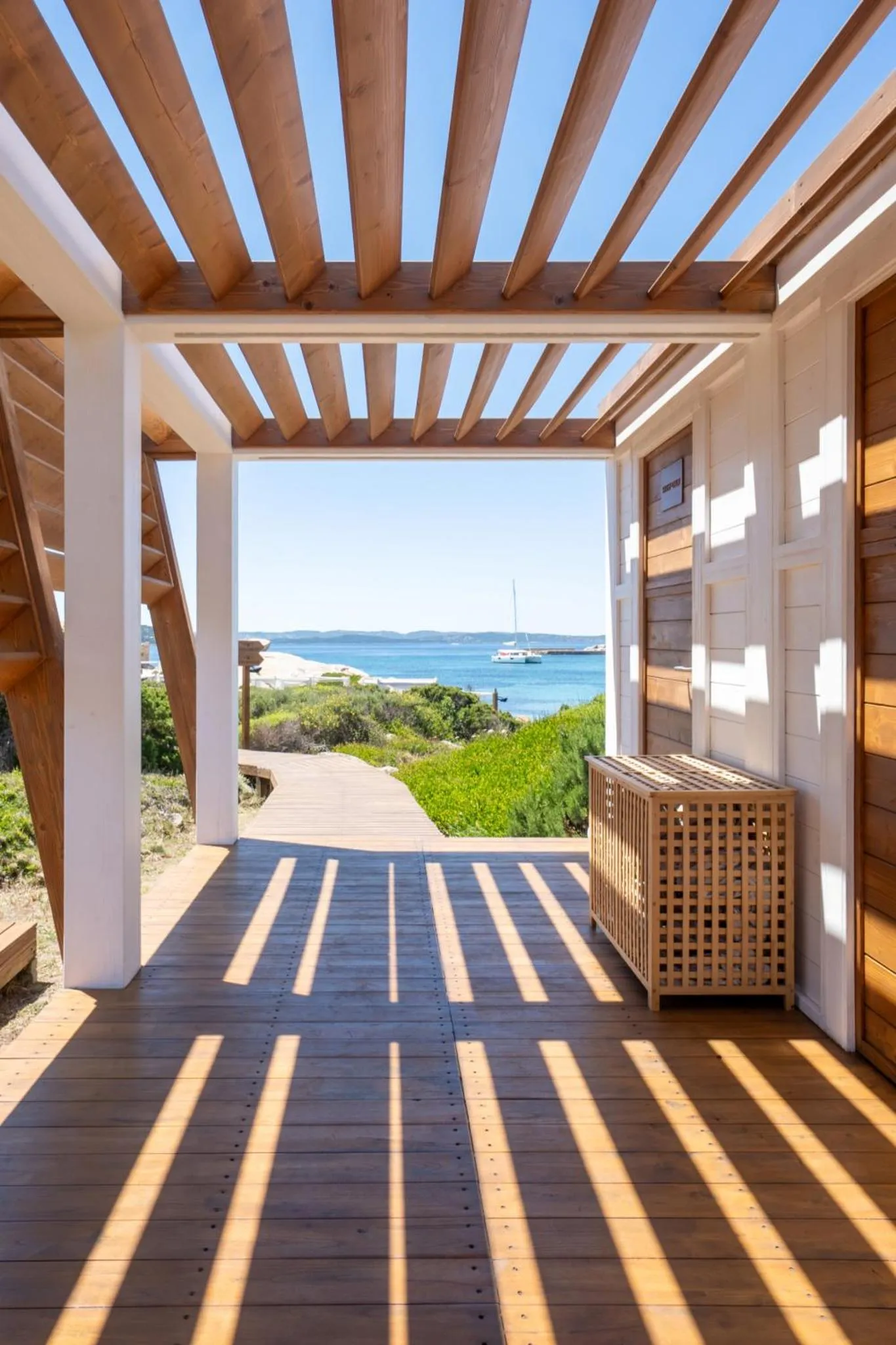 Terrasse en bois avec vue sur la mer et un bateau à l'horizon.