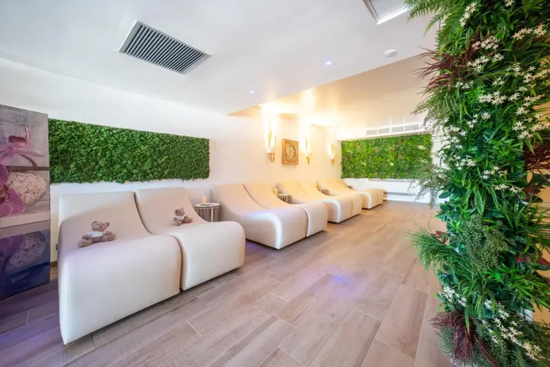 Espace de détente avec des fauteuils blancs et un mur végétal.