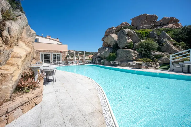 Une piscine rectangulaire bordée d'une terrasse en pierre.