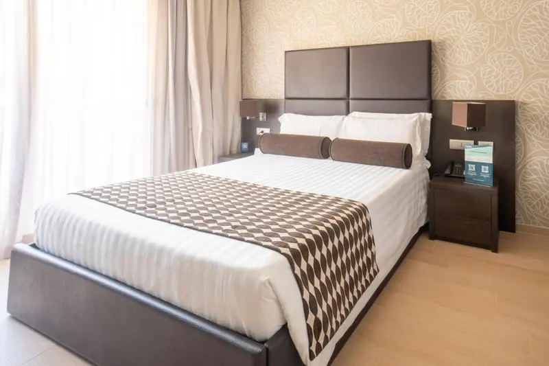 Une chambre avec un grand lit recouvert d'une courtepointe et de coussins.