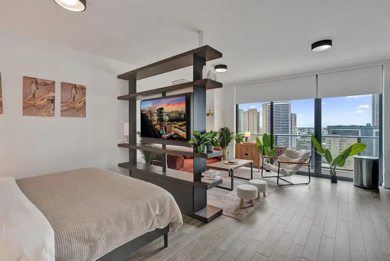 Une chambre moderne avec un grand lit et un espace salon lumineux.