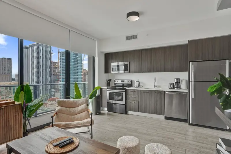 Une cuisine moderne s'ouvre sur un salon lumineux avec vue sur la ville.