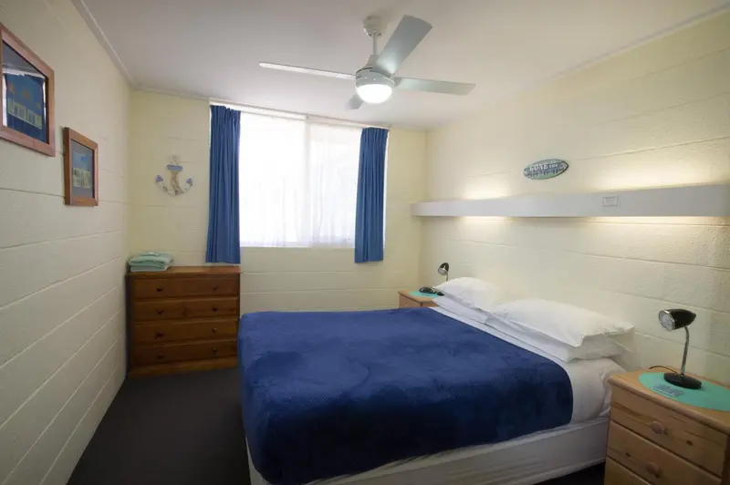 Une chambre lumineuse avec un lit recouvert d'une couverture bleue.