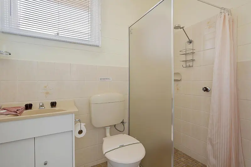 Une salle de bain claire avec douche et lavabo.