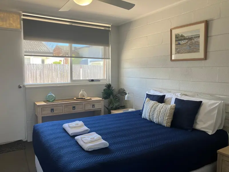 Une chambre lumineuse avec un lit recouvert d'une courtepointe bleue et de coussins.