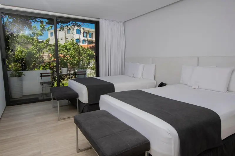 Une chambre lumineuse avec deux lits et une vue sur la végétation.