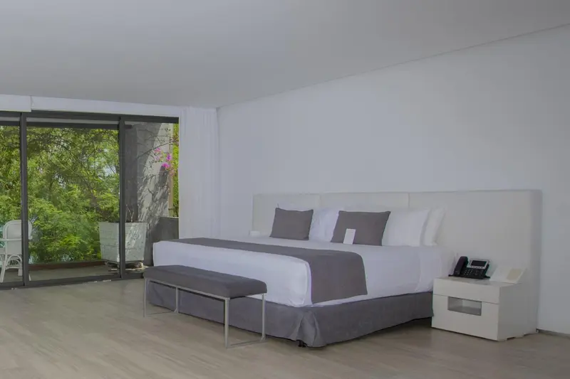 Une chambre lumineuse avec un grand lit et une vue sur la végétation.