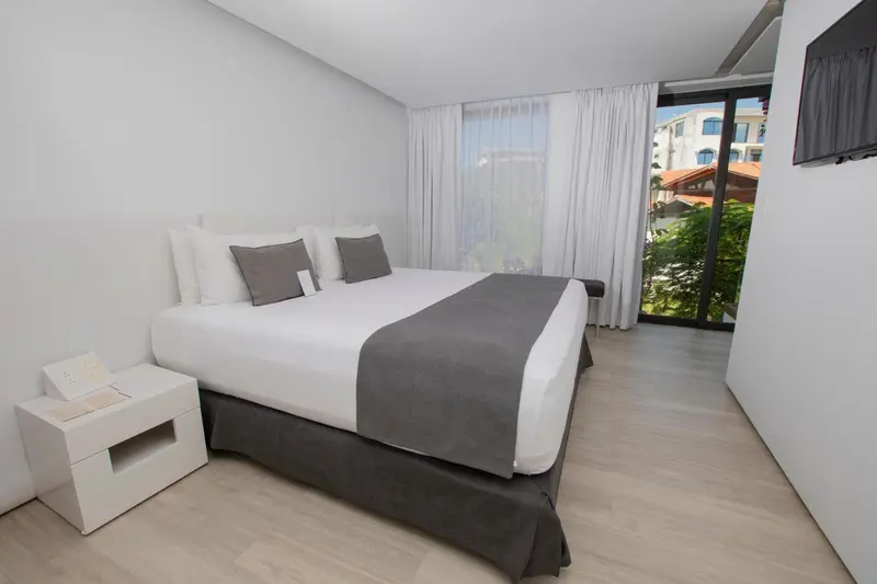 Une chambre lumineuse avec un grand lit et une vue sur la végétation.