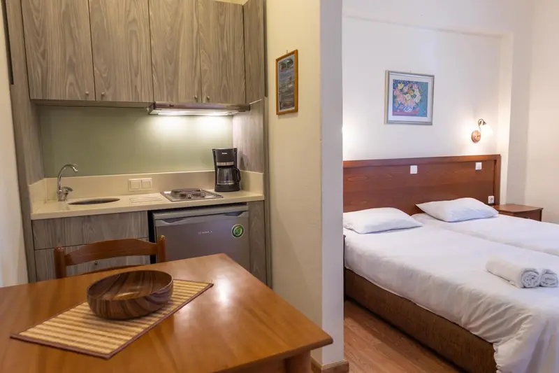 Une kitchenette équipée et un lit dans un intérieur clair.