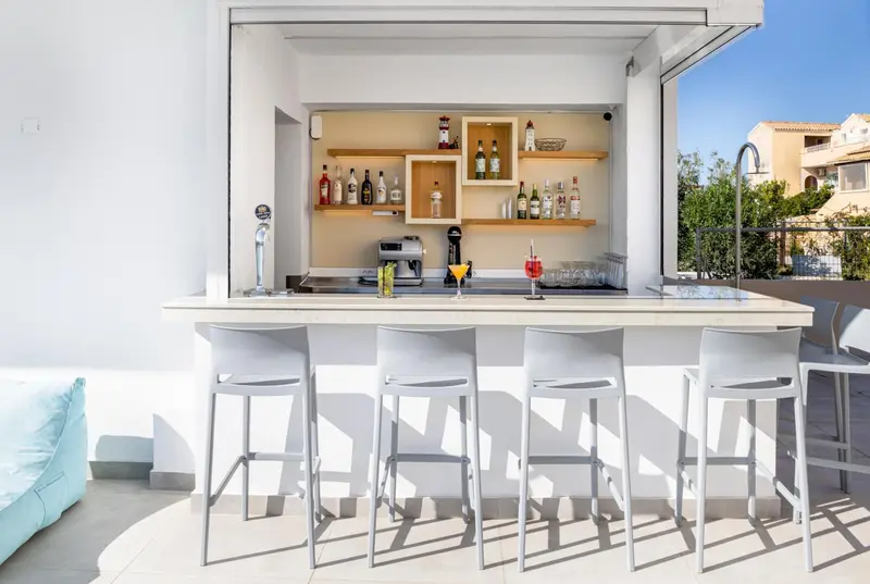 Un comptoir de bar extérieur avec des tabourets et des bouteilles.