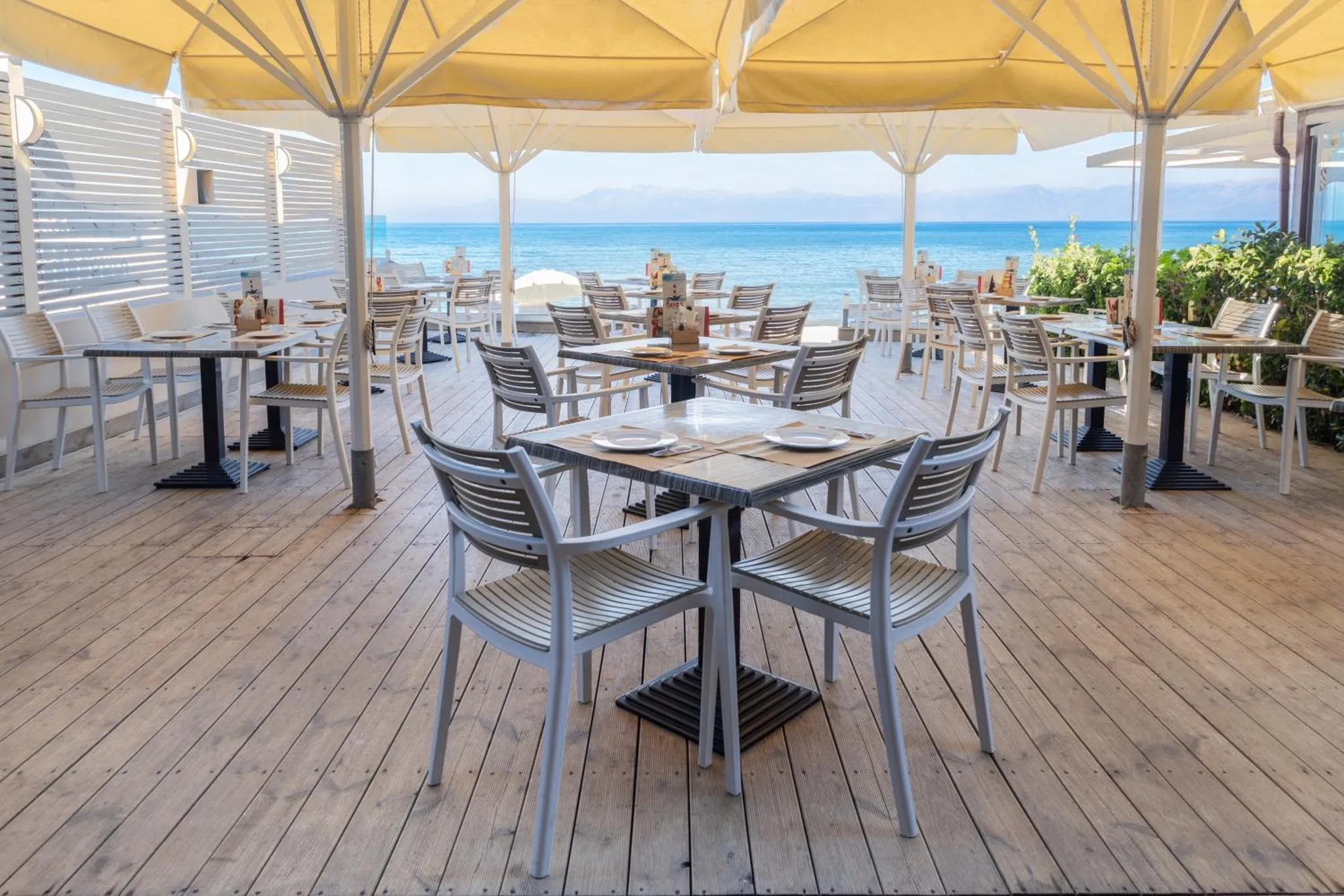 Terrasse de restaurant avec tables et chaises en bord de mer.