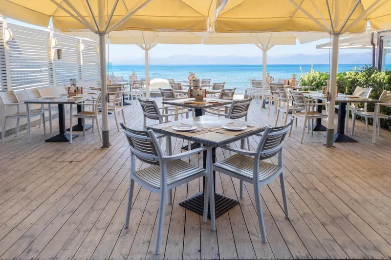 Terrasse de restaurant avec tables et chaises en bord de mer.