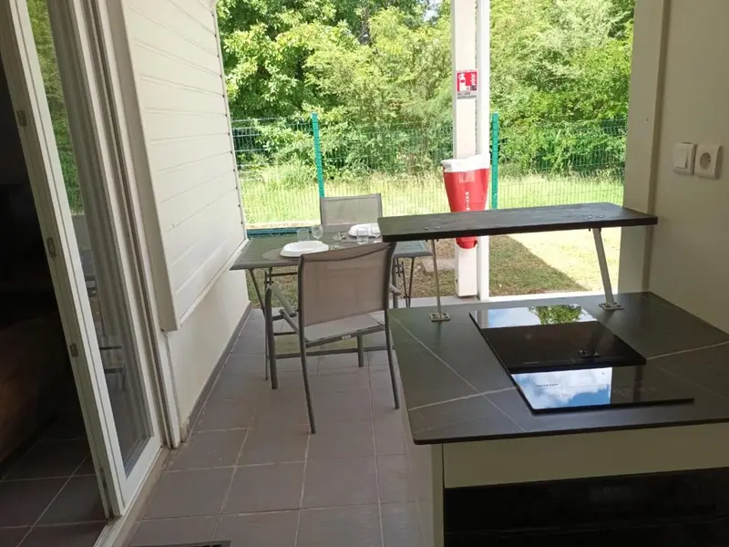 Une terrasse avec une table et des chaises, donnant sur une pelouse verdoyante.