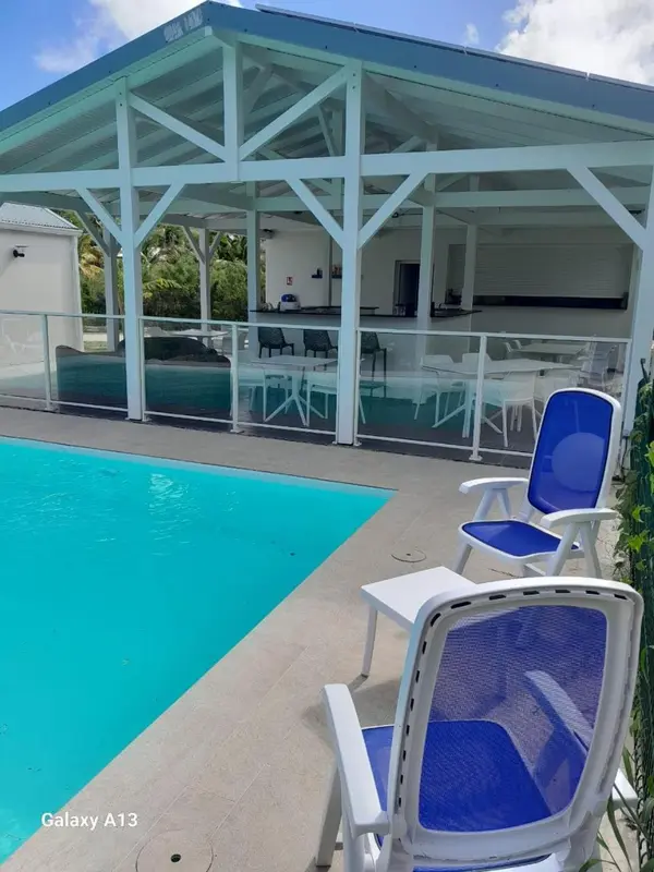 Piscine turquoise avec transats bleus et abri blanc.