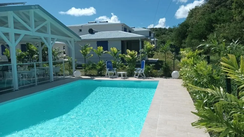 Piscine turquoise bordée d'une terrasse ensoleillée avec des transats.
