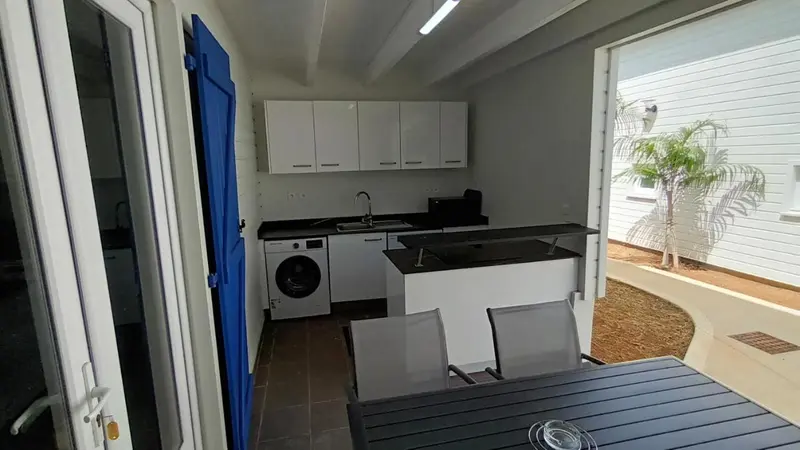 Une cuisine moderne s'ouvre sur une terrasse avec une table et des chaises.