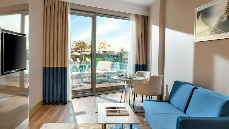 Un salon lumineux s'ouvre sur une terrasse avec vue sur une piscine.