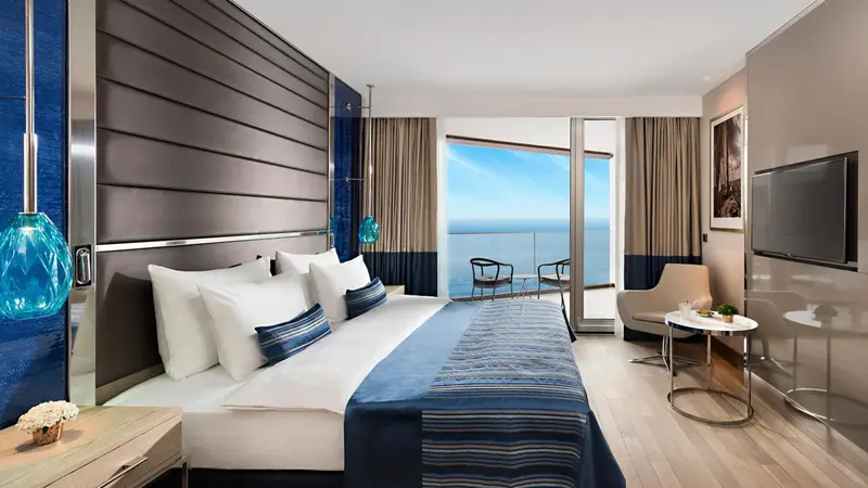 Une chambre lumineuse avec un grand lit donnant sur une vue mer.