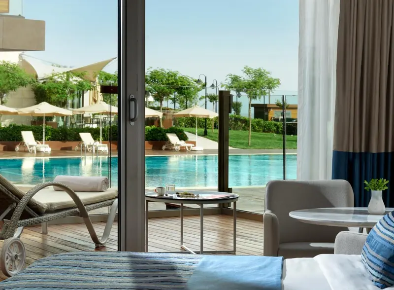 Terrasse avec mobilier de relaxation donnant sur une piscine et un jardin.