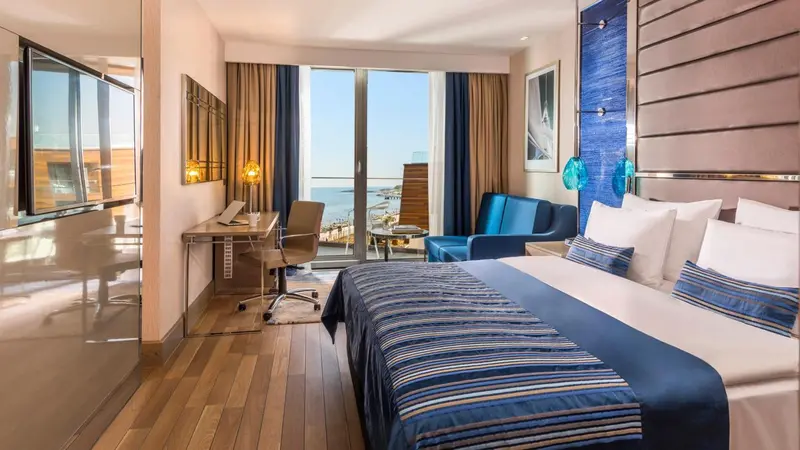 Chambre lumineuse avec un grand lit et une vue sur la mer.