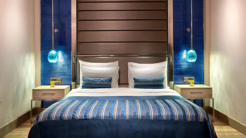 Un lit double est dispose dans une chambre aux tons bleus et bruns.