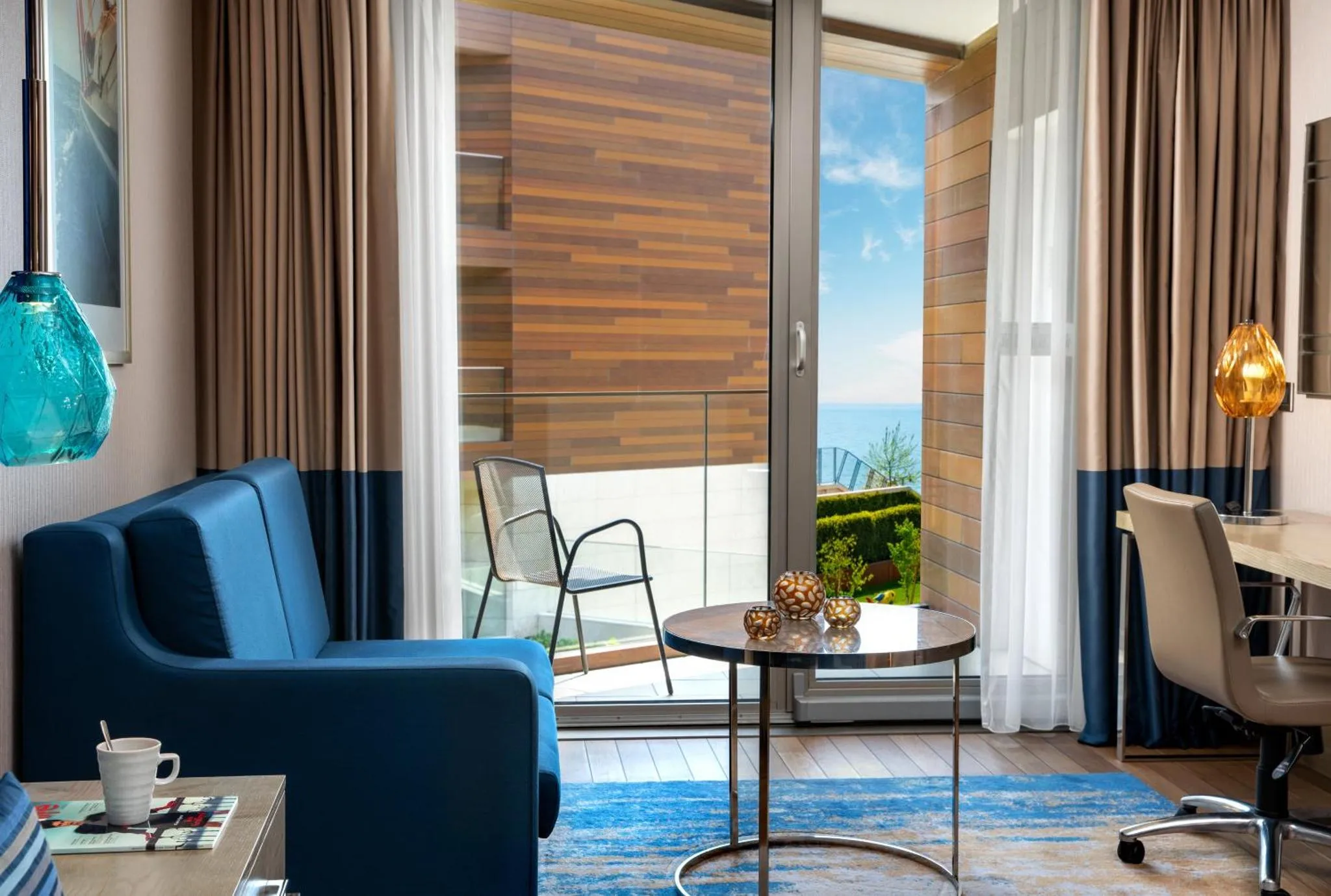 Un salon d'intérieur s'ouvre sur une terrasse avec vue sur la mer.
