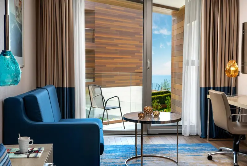 Un salon d'intérieur s'ouvre sur une terrasse avec vue sur la mer.