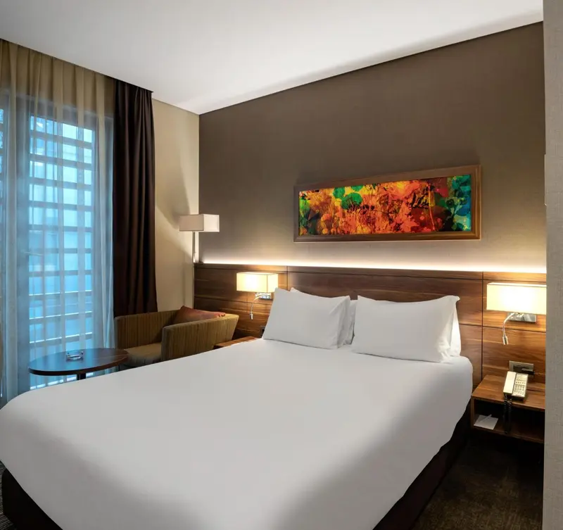 Une chambre d'hôtel lumineuse avec un grand lit et une décoration murale colorée.