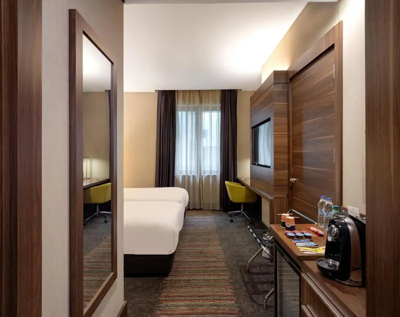 Chambre d'hôtel moderne avec un lit blanc et un bureau.
