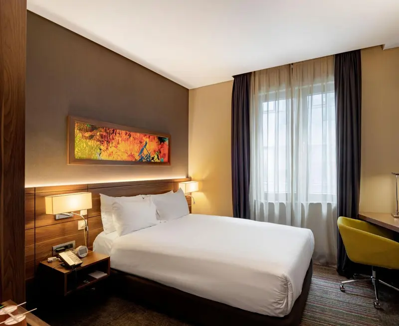 Une chambre d'hôtel lumineuse avec un grand lit et un bureau.