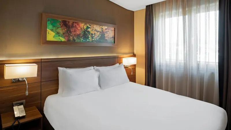 Une chambre d'hôtel lumineuse avec un grand lit et un tableau décoratif.