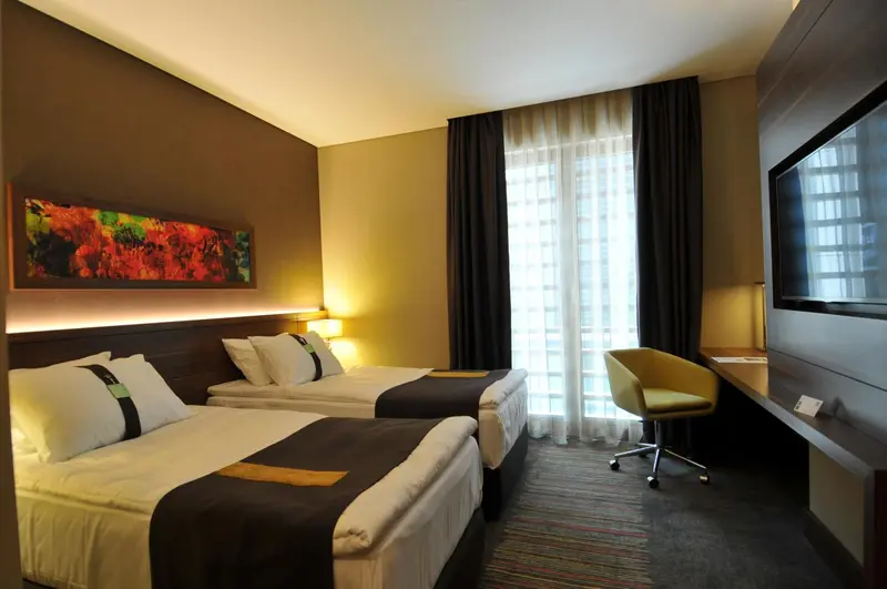 Une chambre moderne avec deux lits et un bureau près d'une fenêtre.