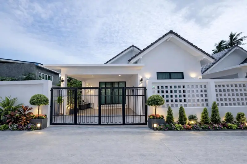 Façade d'une maison blanche avec une entrée et un jardin soigné.