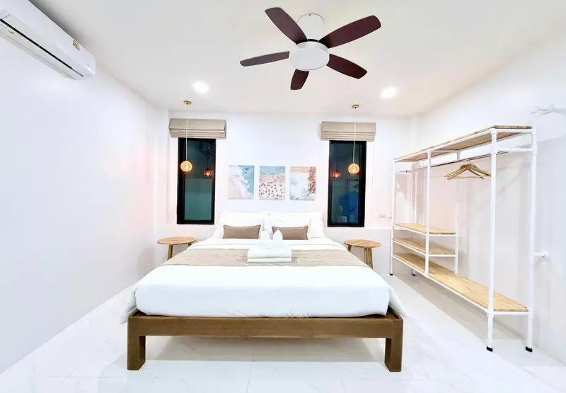 Une chambre lumineuse avec un grand lit et un portant à vêtements.