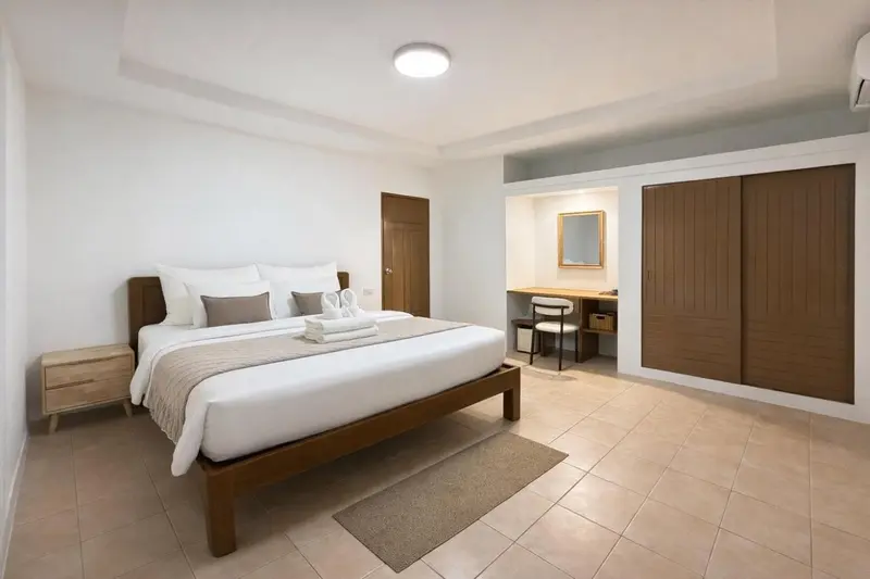 Une chambre lumineuse avec un grand lit et un bureau en bois.