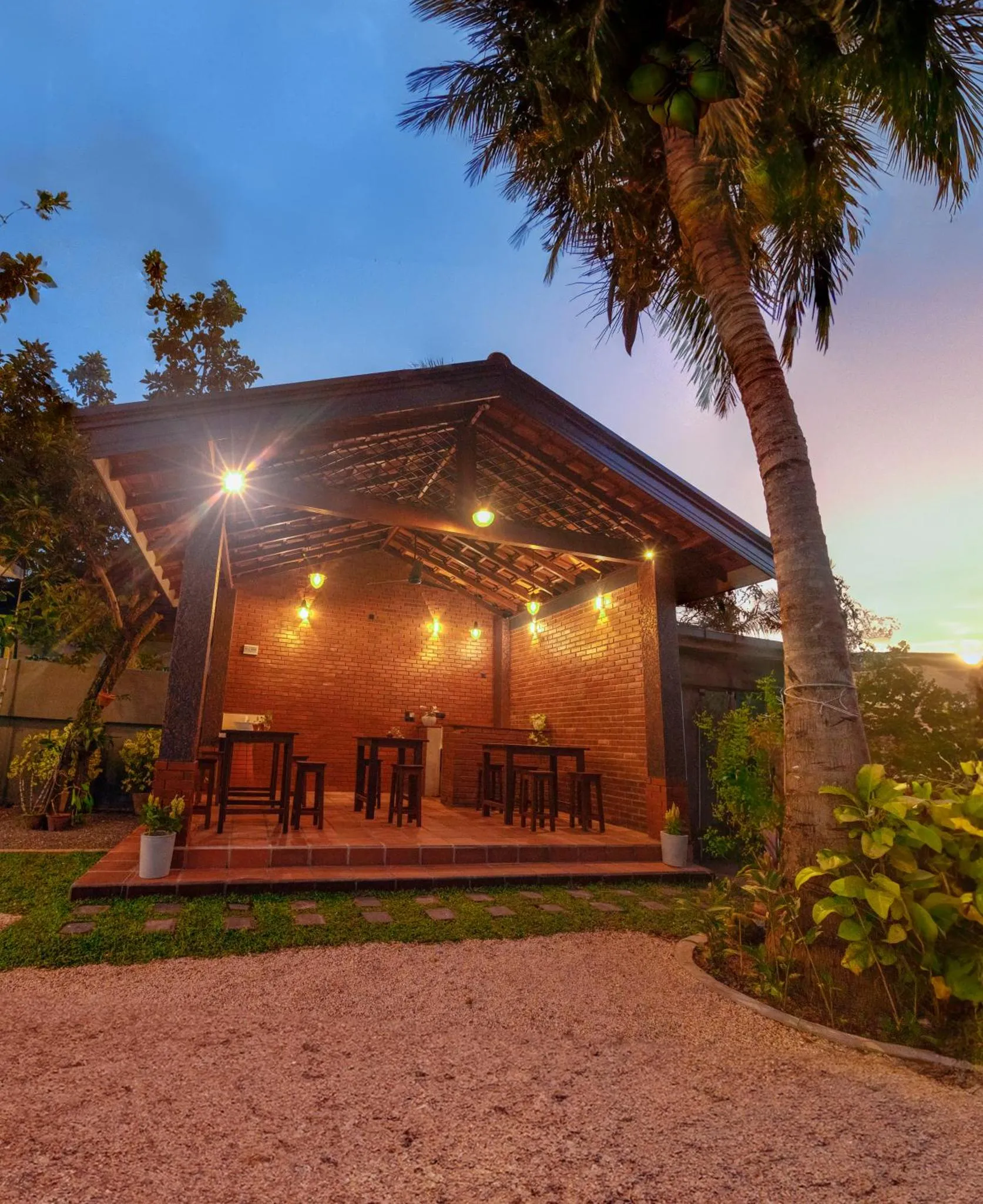 Terrasse ouverte avec tables et chaises éclairées par des lampes.
