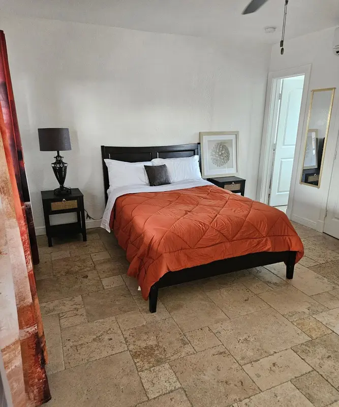 Une chambre lumineuse avec un grand lit recouvert d'une courtepointe orange.