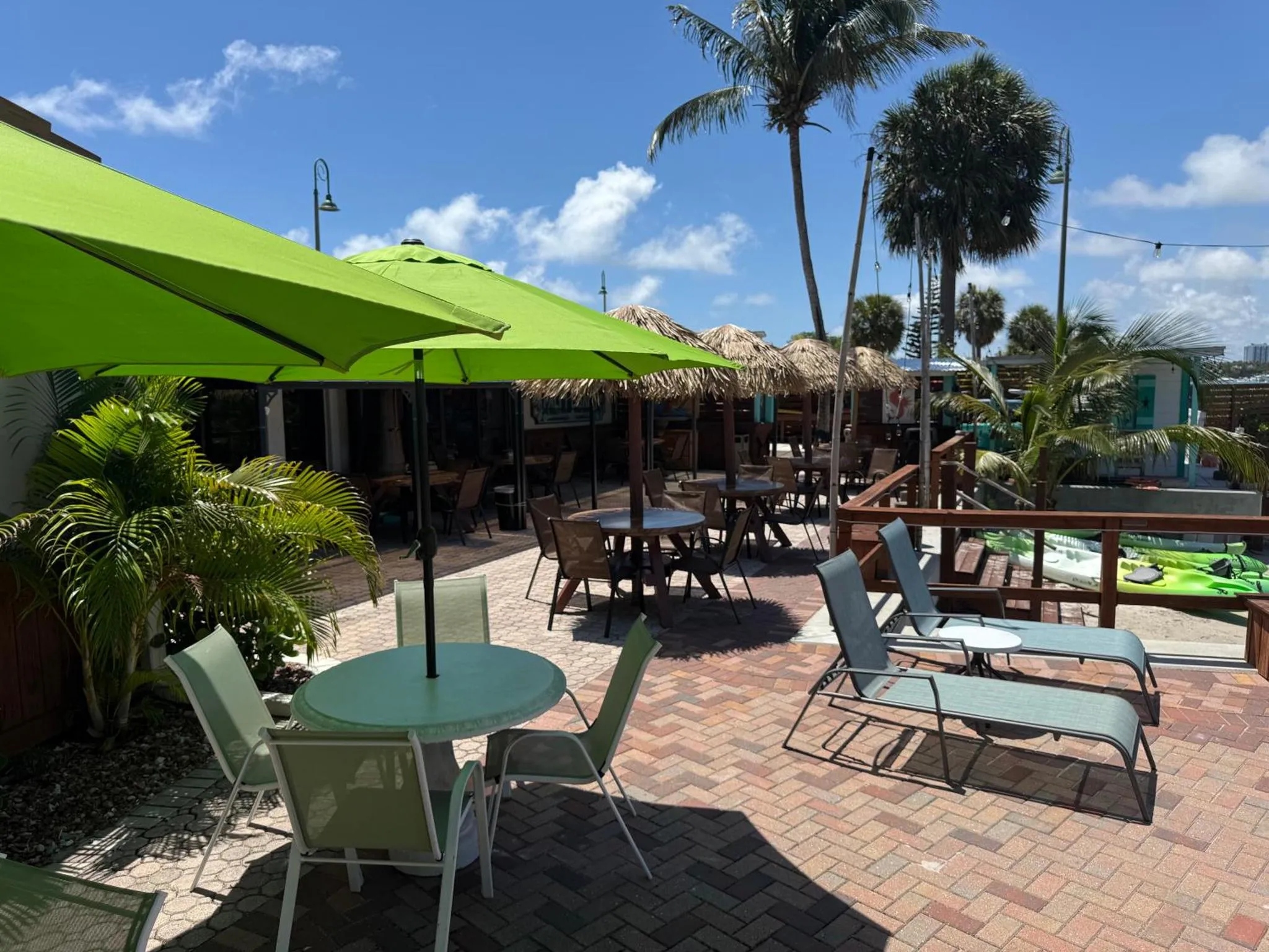 Terrasse ombragée avec tables, chaises et transats.