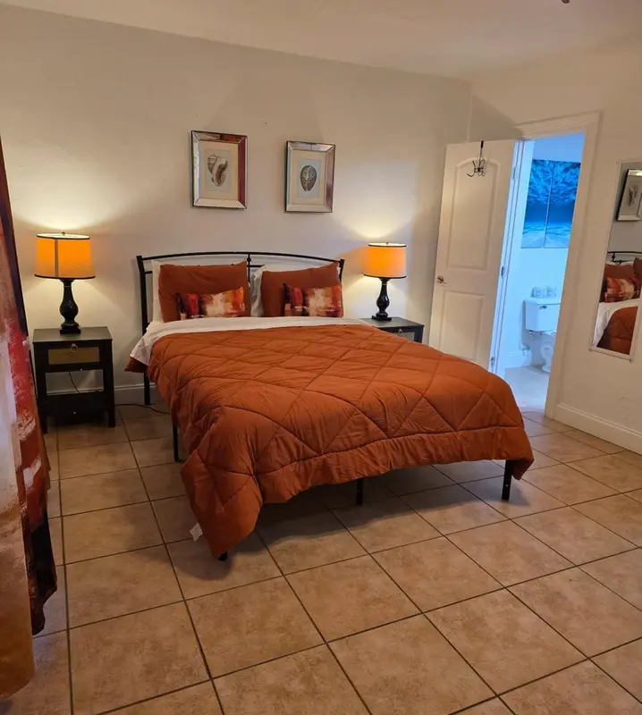 Une chambre avec un lit recouvert d'une courtepointe orange et deux tables de chevet.